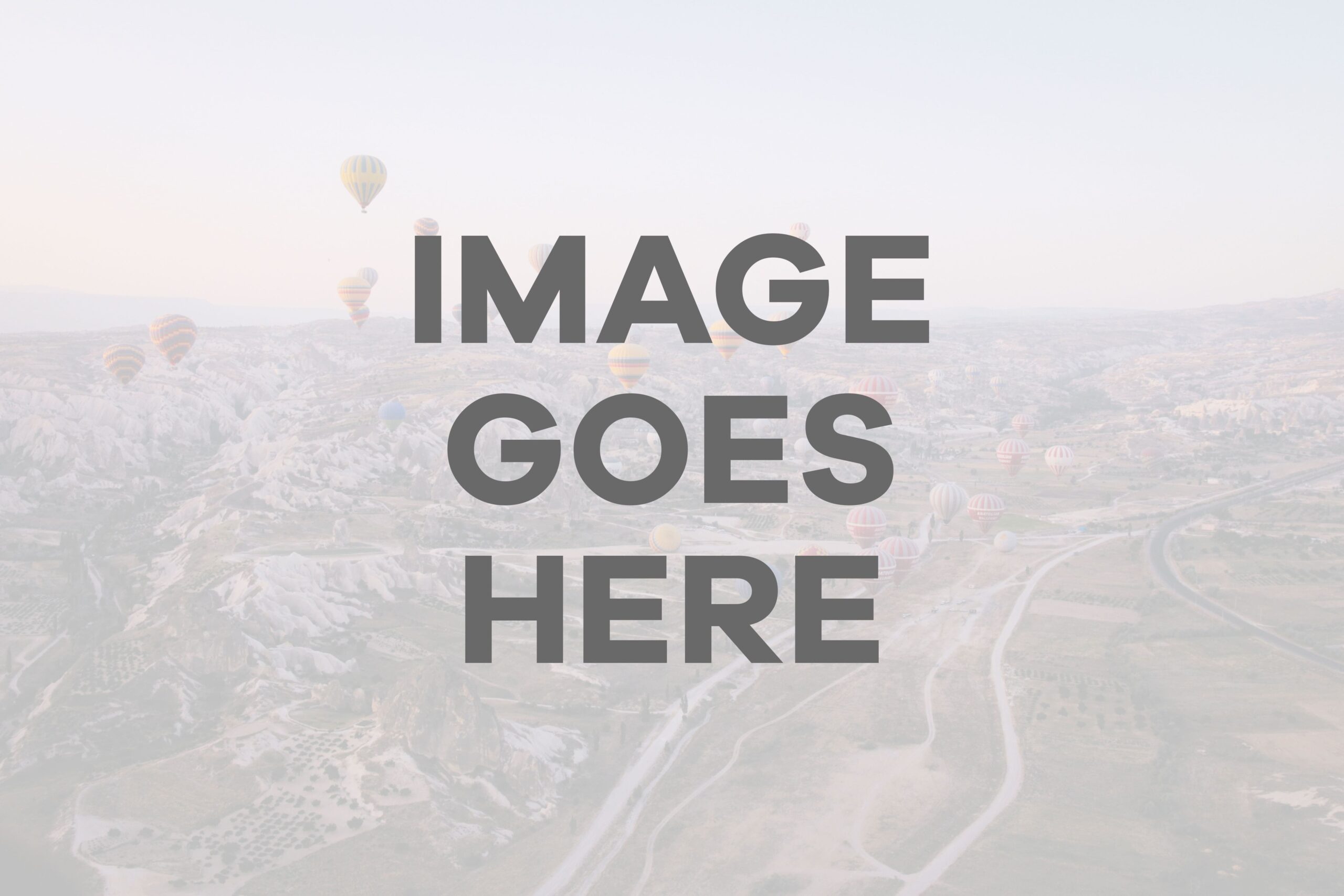 Aerial view of landscape with hot air balloons floating above fields and roads.