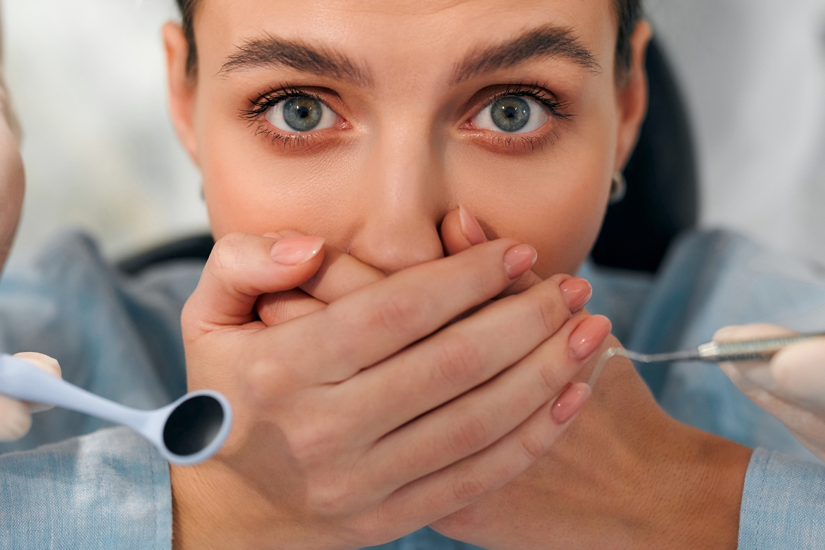 Woman covering mouth during dental exam due to bleeding gum concerns